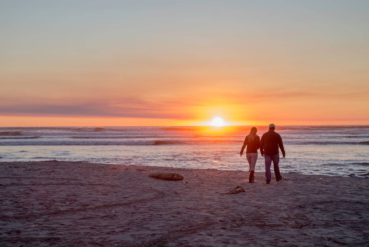 A couple walks along Kalaloch Beach at sunset