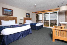 Kalaloch Main Lodge room with two beds, a sofa, wall art, and sliding glass doors opening to a balcony with an outdoor view.