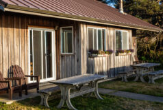 Kalaloch Cabin with a metal roof, picnic tables, flower boxes, and Adirondack chairs outside.