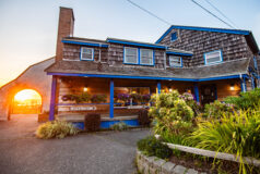 Kalaloch Main Lodge at sunset, surrounded by greenery and flowers, with registration signs visible.