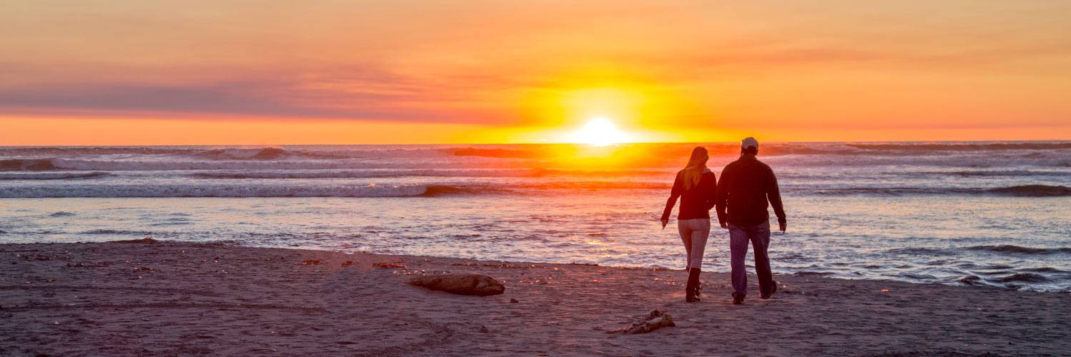 A couple walks along Kalaloch Beach in Olympic National Park at sunset