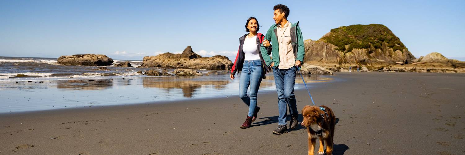 A couple walking their dog on the beach near Kalaloch Lodge