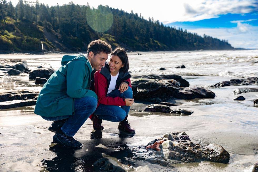 Two visitors looking at a starfish on the beach at Kalaloch Lodge